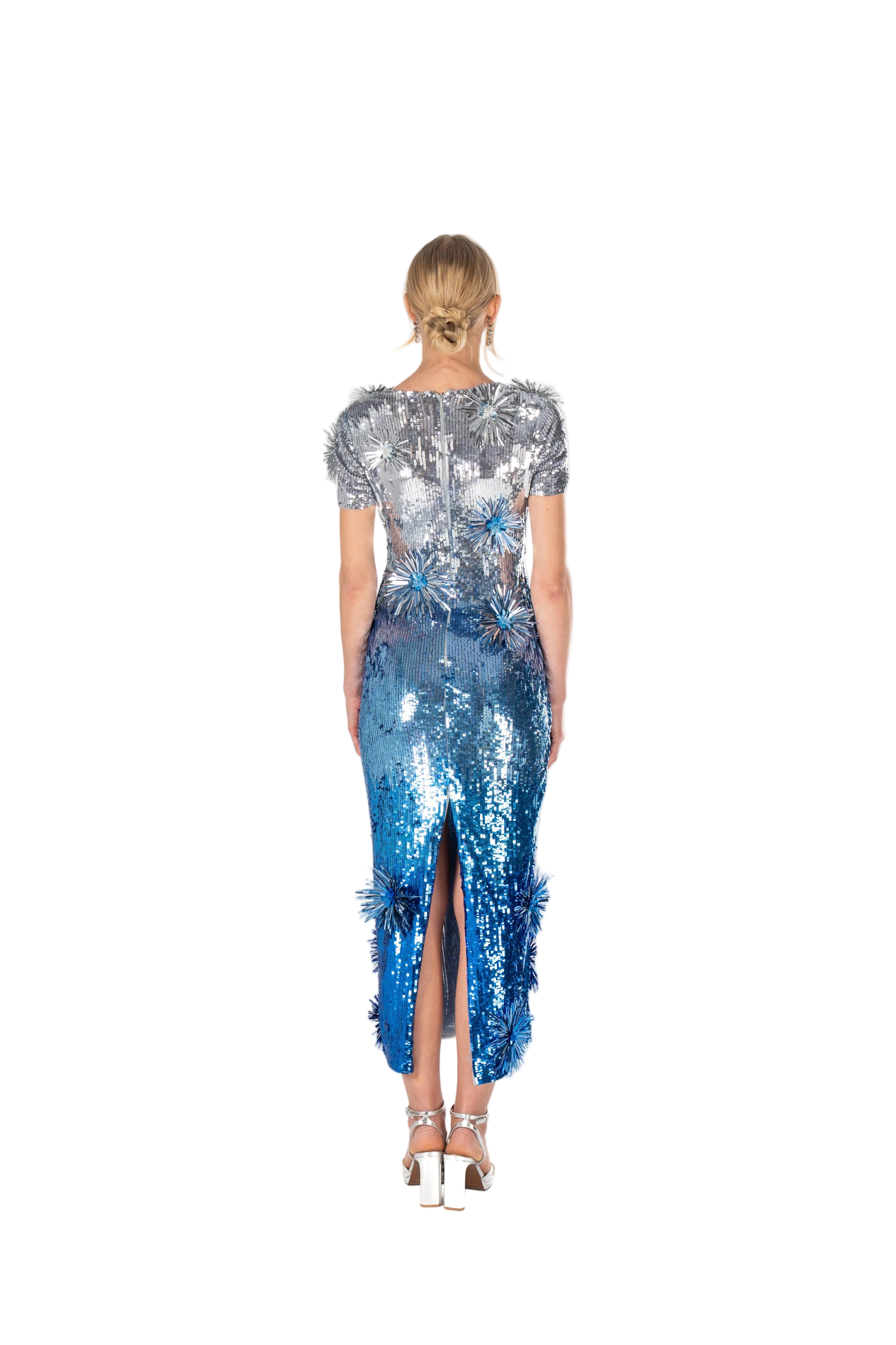 Woman wearing a blue sequin dress with a high slit on a white background